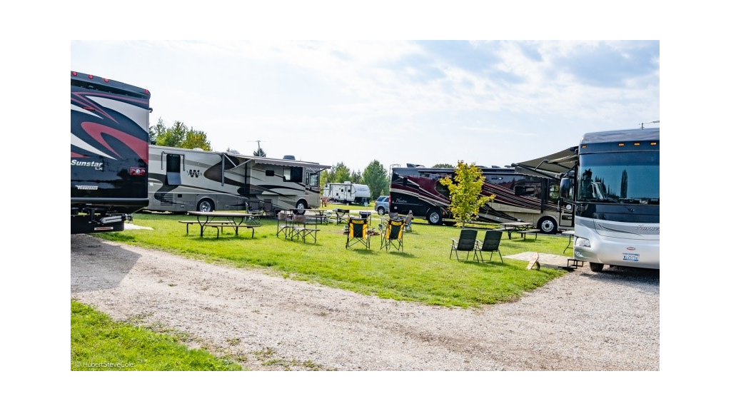 Four motorhomes parked with chairs and picnic tables on the lawn between them.